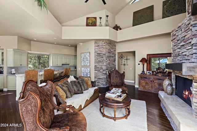 living room with a stone fireplace, ceiling fan, high vaulted ceiling, and dark hardwood / wood-style floors