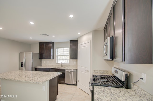 kitchen featuring recessed lighting, a kitchen island, a sink, dark brown cabinets, and appliances with stainless steel finishes