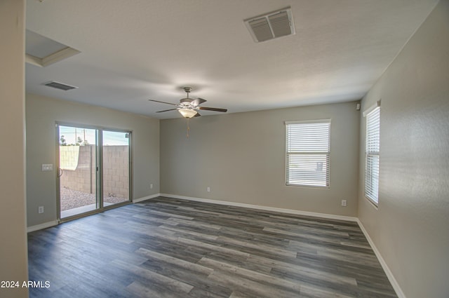 empty room featuring dark wood-style floors, visible vents, ceiling fan, and baseboards