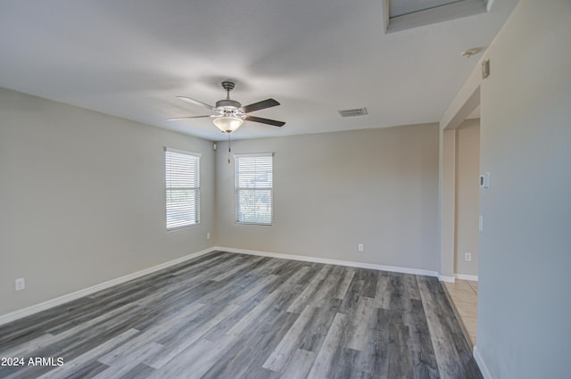 empty room featuring baseboards, visible vents, ceiling fan, and wood finished floors