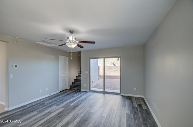 spare room with stairway, wood finished floors, a ceiling fan, and baseboards