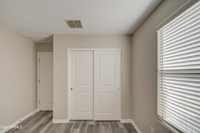 unfurnished bedroom with baseboards, a closet, visible vents, and wood finished floors