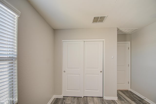 unfurnished bedroom featuring a closet, wood finished floors, visible vents, and baseboards