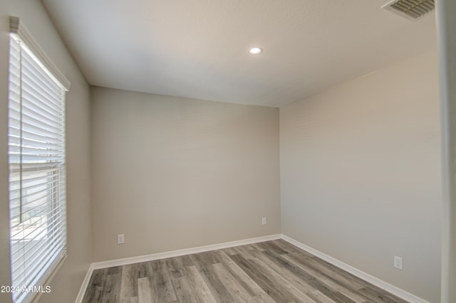 empty room with baseboards, visible vents, wood finished floors, and recessed lighting