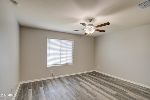 unfurnished room featuring a ceiling fan, baseboards, visible vents, and wood finished floors