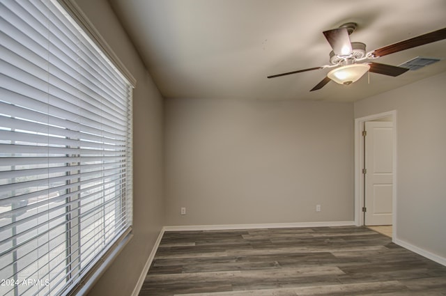 unfurnished room with dark wood-style floors, visible vents, and baseboards