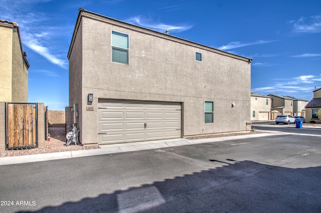 view of property exterior featuring a garage, fence, and stucco siding