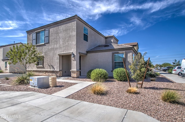 traditional-style home featuring a tile roof and stucco siding