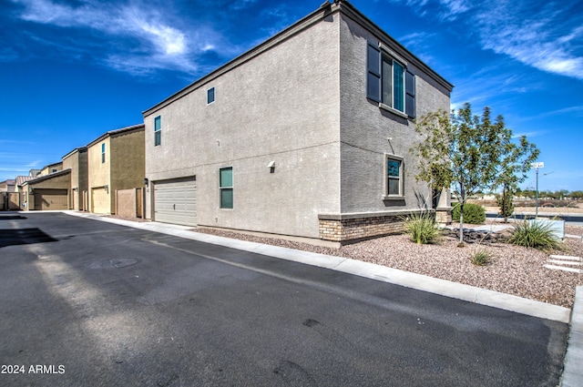 view of side of home with an attached garage and stucco siding