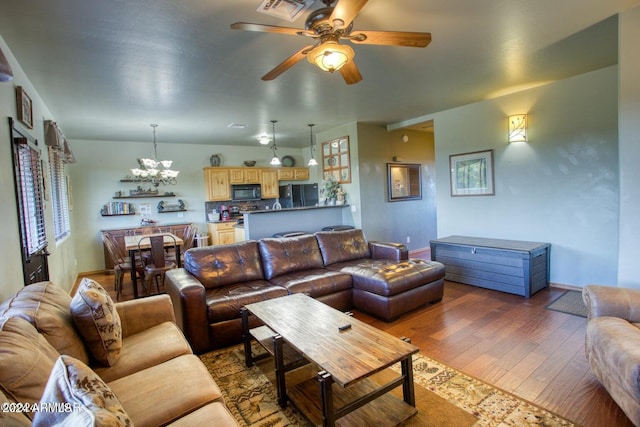 living room featuring ceiling fan with notable chandelier and dark hardwood / wood-style floors