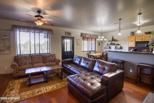 living room featuring ceiling fan with notable chandelier and dark hardwood / wood-style flooring