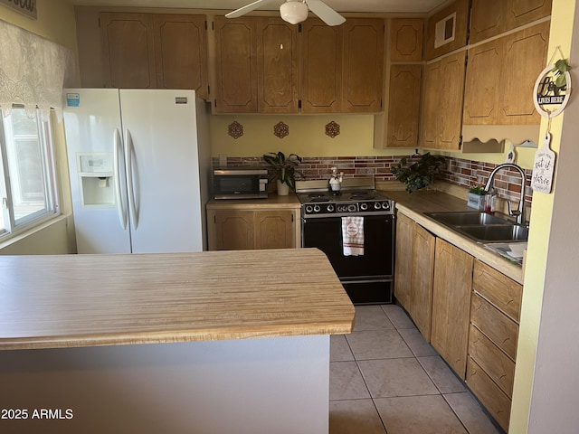 kitchen with stainless steel microwave, black range with electric stovetop, light countertops, white fridge with ice dispenser, and a sink