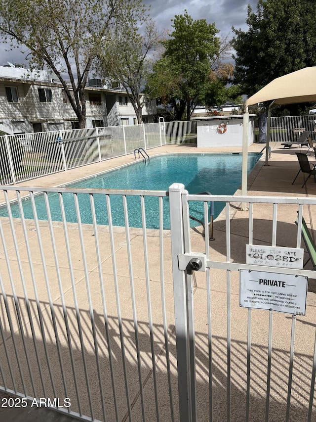 pool with a patio area and fence