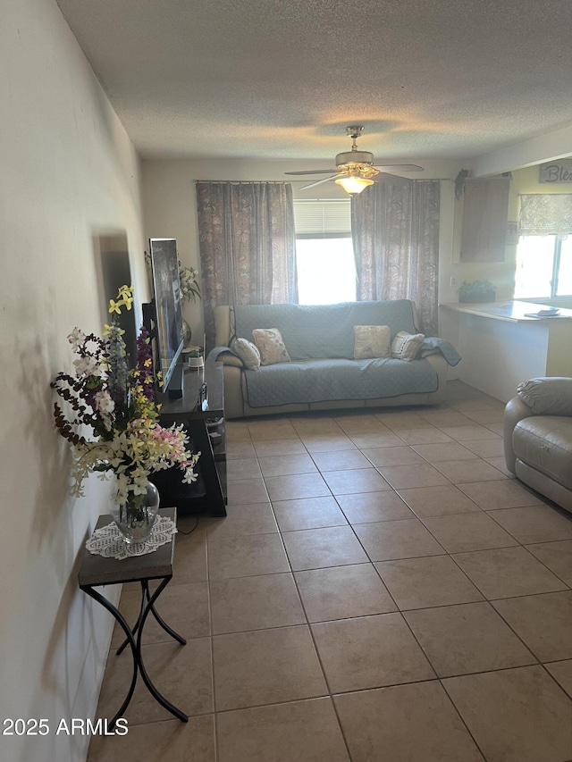 living area with a textured ceiling, a ceiling fan, and tile patterned floors