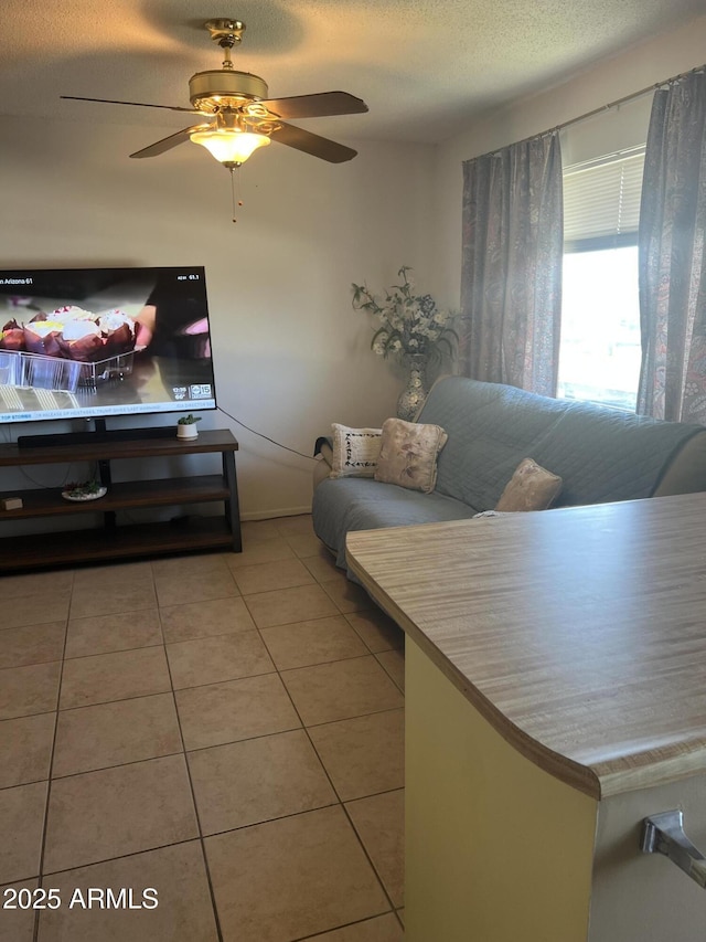 living room featuring ceiling fan, a textured ceiling, and tile patterned floors