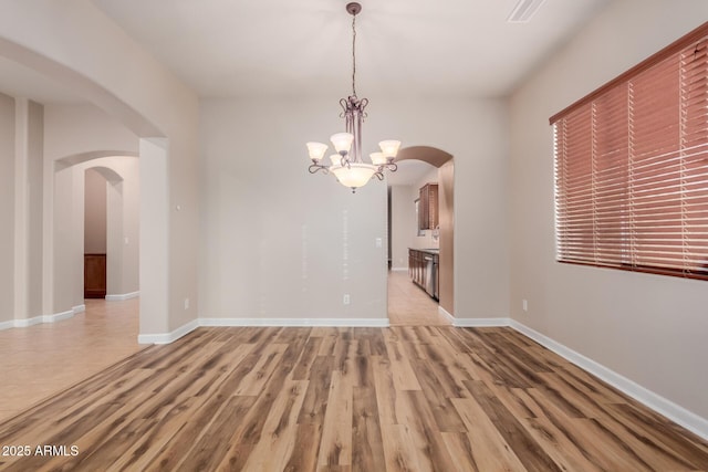 unfurnished dining area featuring light hardwood / wood-style flooring and an inviting chandelier