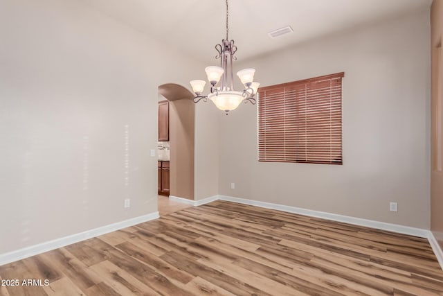 empty room featuring light hardwood / wood-style floors and a chandelier