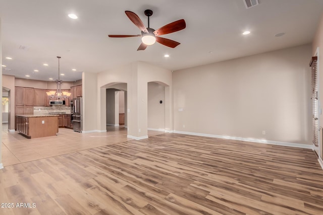 unfurnished living room with light hardwood / wood-style floors and ceiling fan with notable chandelier