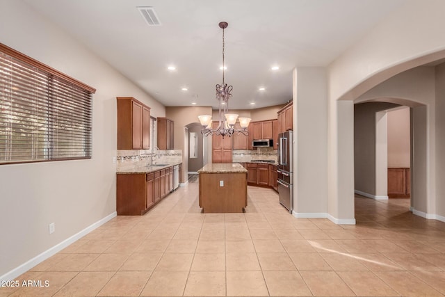 kitchen with hanging light fixtures, appliances with stainless steel finishes, backsplash, light tile patterned floors, and a center island