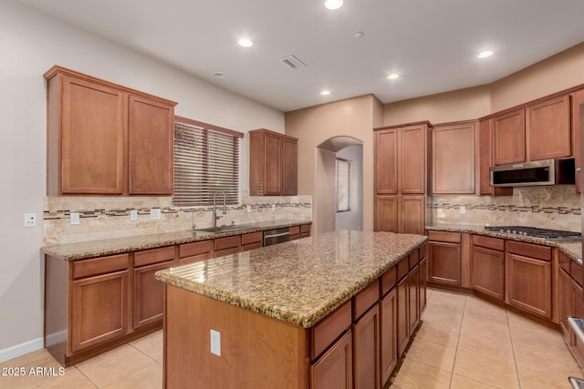 kitchen featuring sink, a kitchen island, light tile patterned floors, and appliances with stainless steel finishes