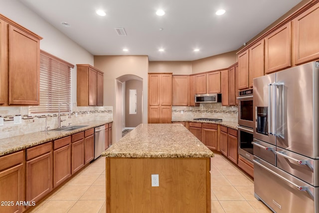 kitchen with a kitchen island, light tile patterned flooring, sink, and appliances with stainless steel finishes