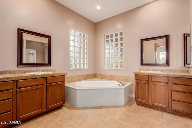 bathroom with tile patterned floors, a tub to relax in, and vanity