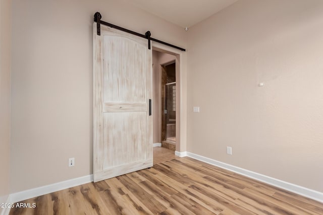 unfurnished bedroom featuring a barn door and wood-type flooring