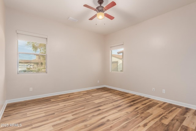 spare room featuring ceiling fan, light hardwood / wood-style flooring, and a healthy amount of sunlight