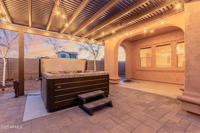 patio terrace at dusk featuring a hot tub