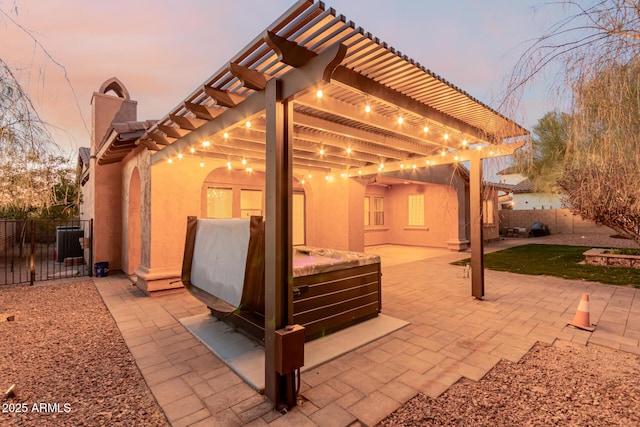 patio terrace at dusk featuring cooling unit and a pergola