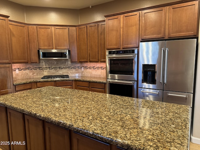 kitchen featuring appliances with stainless steel finishes, dark stone counters, and tasteful backsplash