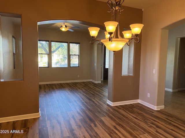 unfurnished dining area with ceiling fan with notable chandelier and dark hardwood / wood-style flooring