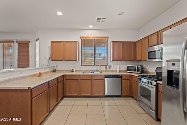 kitchen featuring sink, stainless steel appliances, kitchen peninsula, and light tile patterned floors