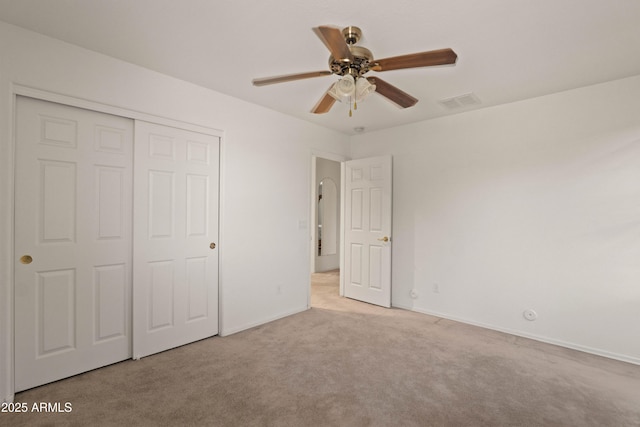 unfurnished bedroom with ceiling fan, a closet, and light carpet