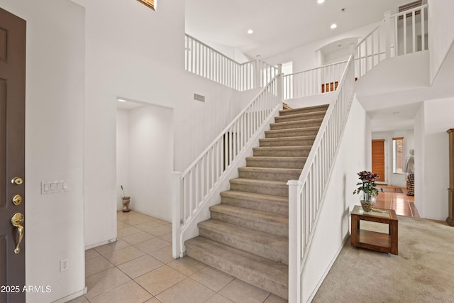 stairs featuring a high ceiling and tile patterned floors