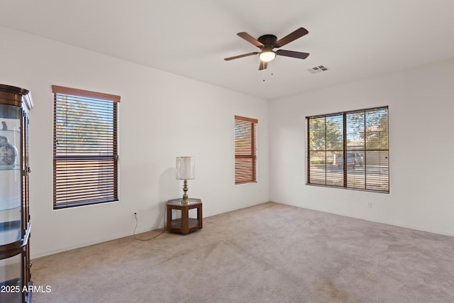 empty room featuring ceiling fan, light carpet, and a healthy amount of sunlight