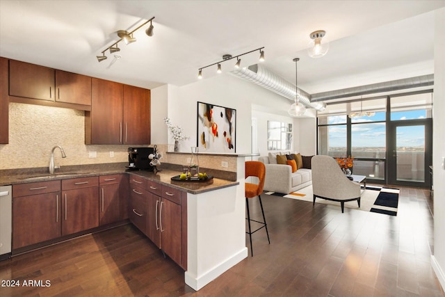 kitchen with dark hardwood / wood-style flooring, track lighting, a breakfast bar, sink, and decorative light fixtures