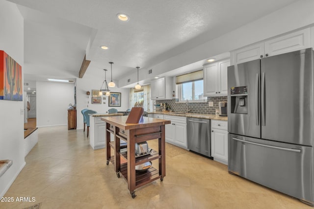 kitchen featuring stainless steel appliances, a sink, white cabinetry, hanging light fixtures, and tasteful backsplash