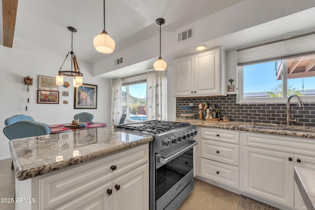 kitchen with a sink, visible vents, white cabinets, tasteful backsplash, and stainless steel range