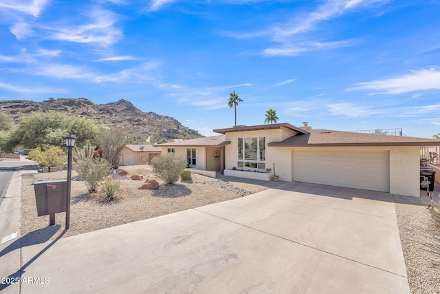 view of front of home featuring a mountain view, driveway, an attached garage, and stucco siding