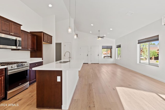 kitchen featuring ceiling fan, sink, hanging light fixtures, stainless steel appliances, and a center island with sink