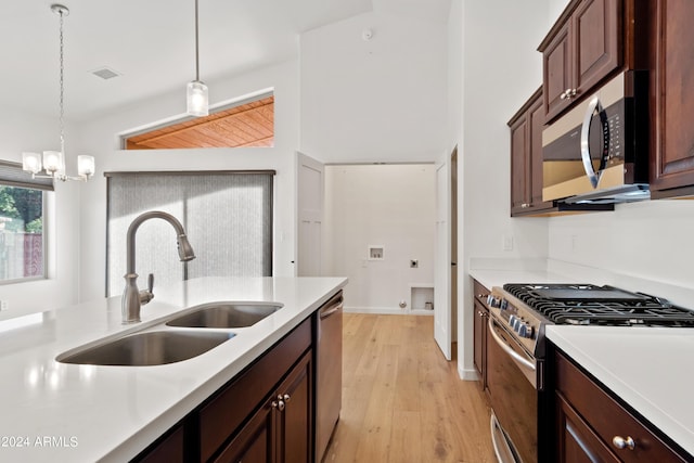 kitchen with stainless steel appliances, vaulted ceiling, sink, decorative light fixtures, and a notable chandelier