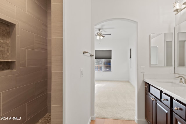 bathroom with a tile shower, vanity, and ceiling fan