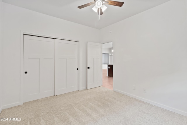 unfurnished bedroom featuring light carpet, a closet, and ceiling fan