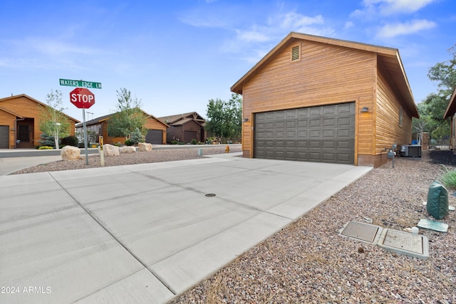 view of side of property with an outdoor structure, central AC unit, and a garage