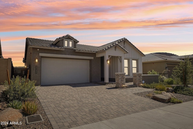 view of front of property featuring fence, a tiled roof, stucco siding, decorative driveway, and a garage