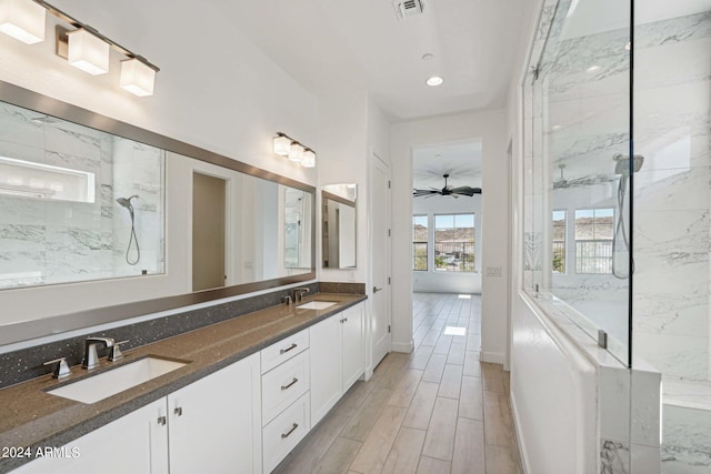 full bathroom featuring a sink, a marble finish shower, wood finish floors, and visible vents