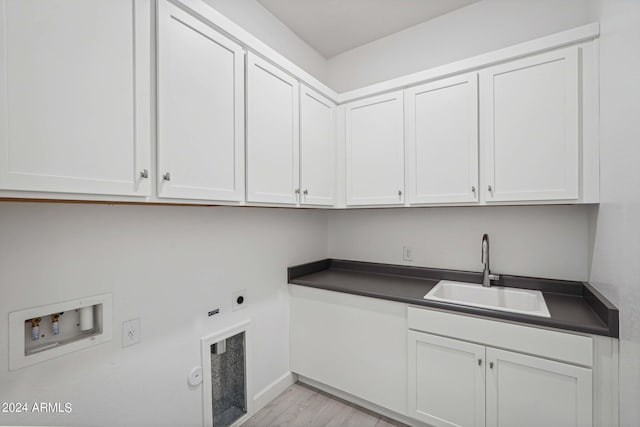 clothes washing area featuring light wood-type flooring, washer hookup, a sink, cabinet space, and hookup for an electric dryer