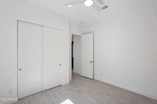 unfurnished bedroom with baseboards, visible vents, light wood-style flooring, ceiling fan, and a closet