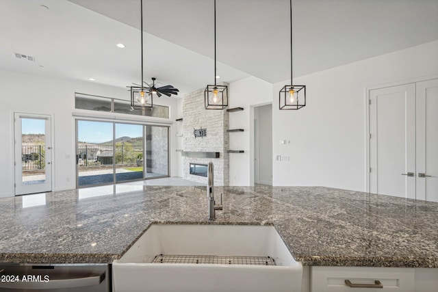 kitchen with visible vents, a sink, open floor plan, a stone fireplace, and stainless steel dishwasher